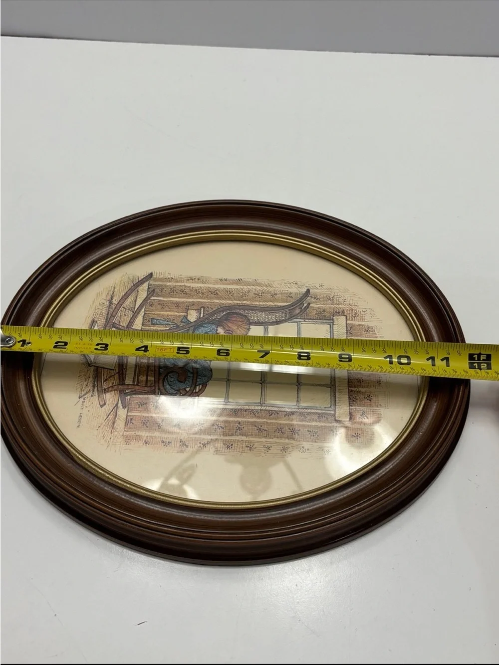 Vintage oval framed wall art piece featuring a girl in a rocking chair by a wind